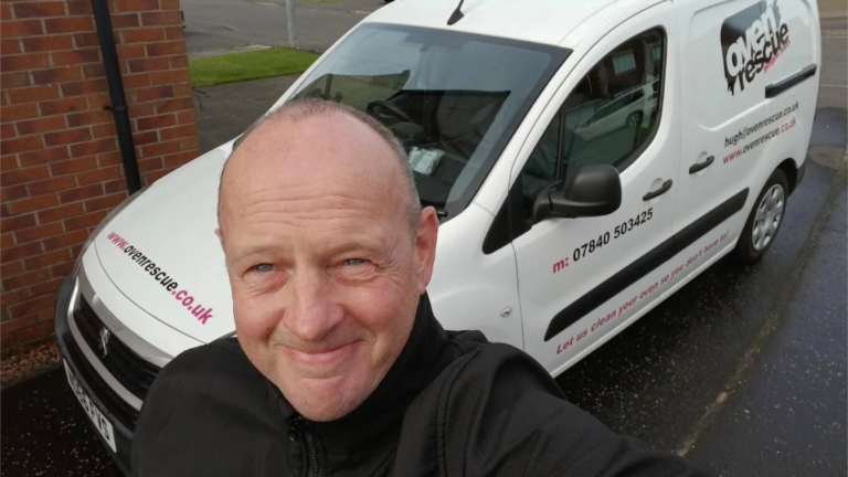A smiling man standing in front of an Oven Rescue van