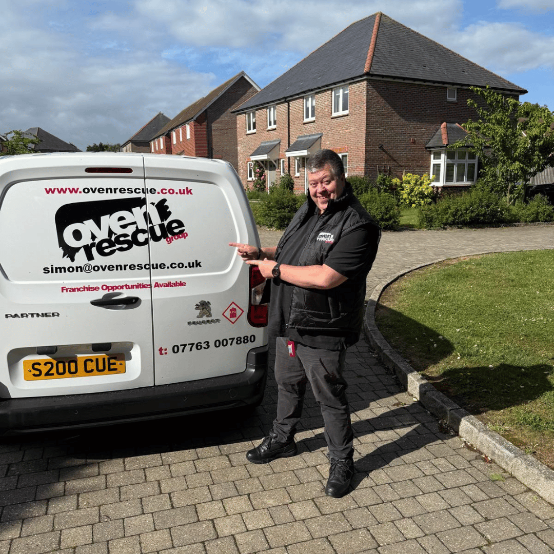 Smiling oven rescue franchise owner standing beside a branded van displaying the oven rescue logo and website