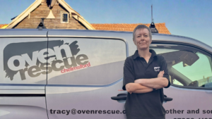 Woman with arms crossed smiling by an Oven Rescue van.