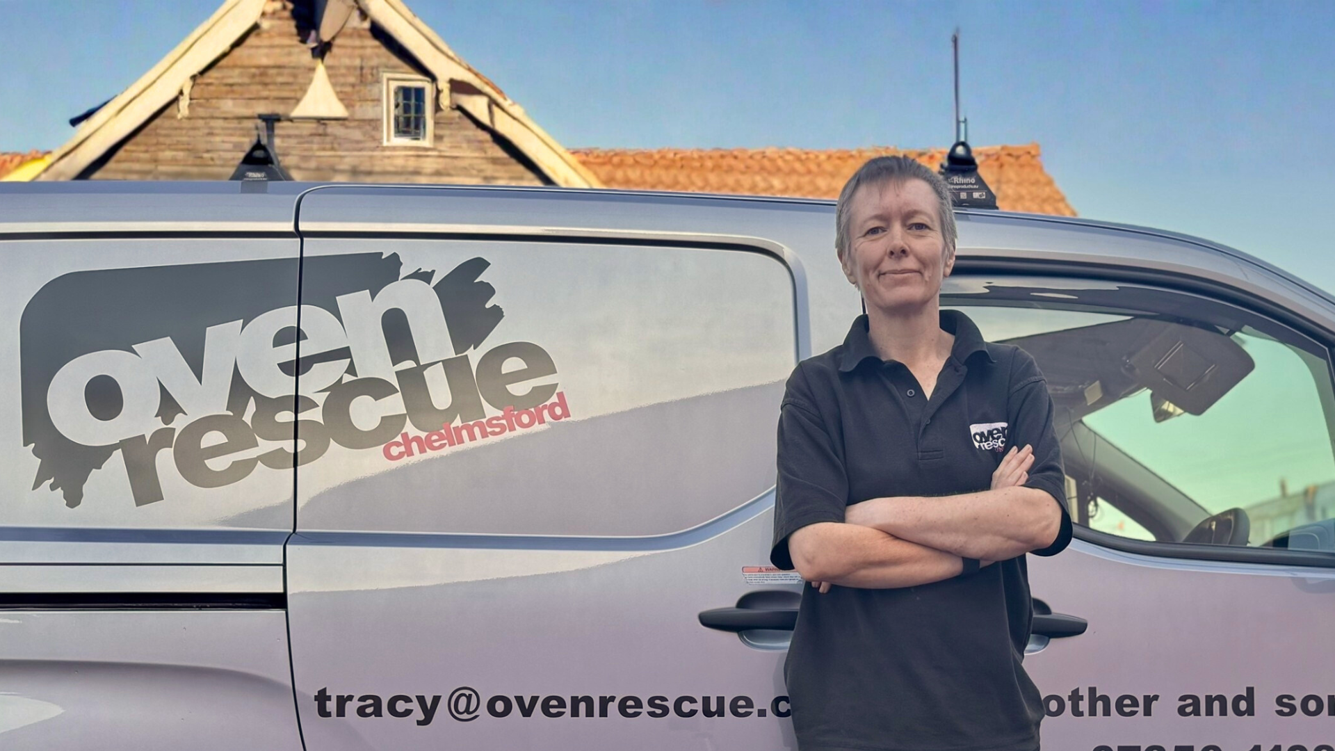 Woman with arms crossed smiling by an Oven Rescue van.