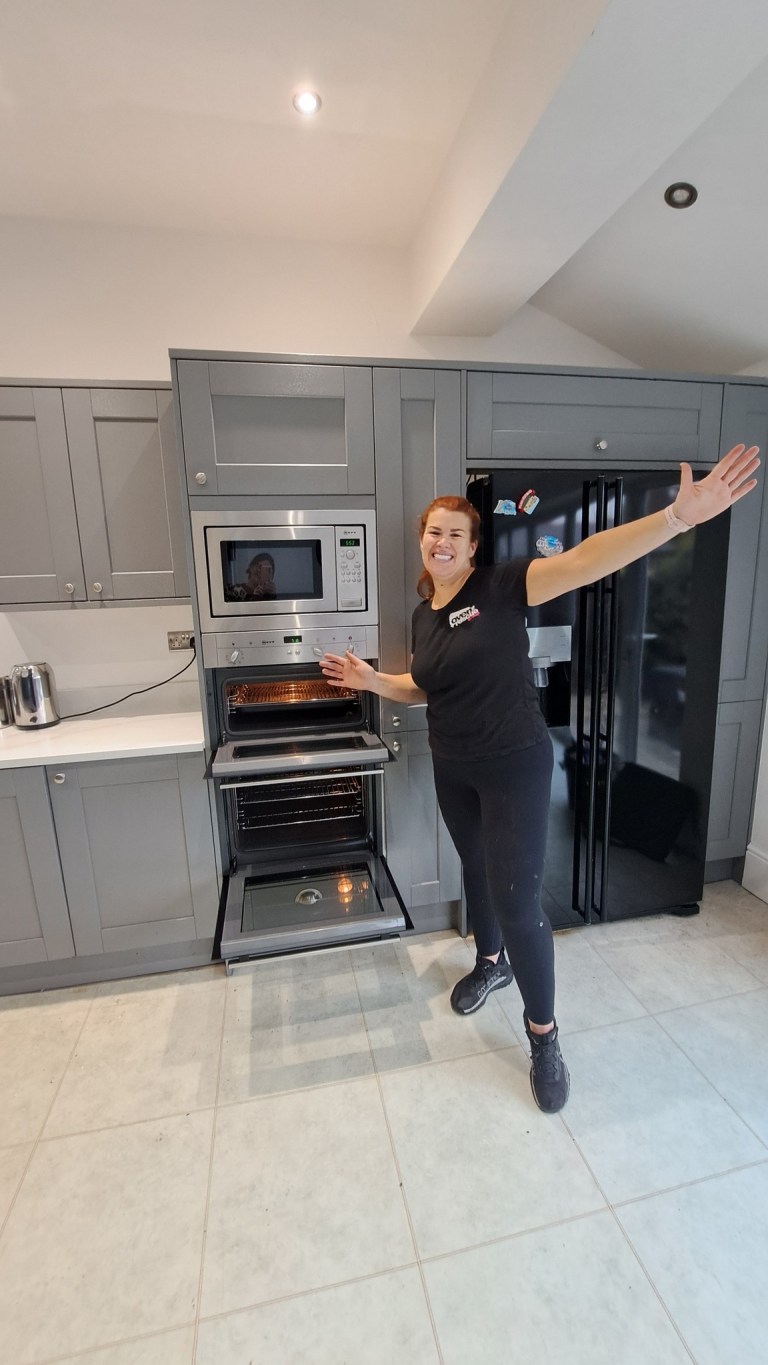 Lady smiling in front of a clean oven smiling