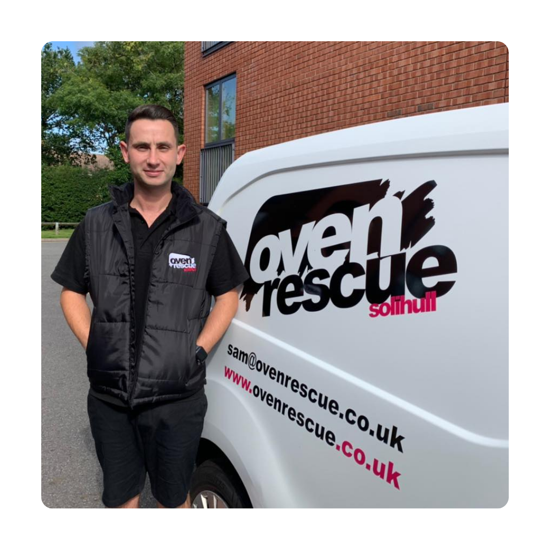A man in a black vest stands next to a white van with "oven rescue Solihull" logo. The setting is outdoors with a brick building and greenery.