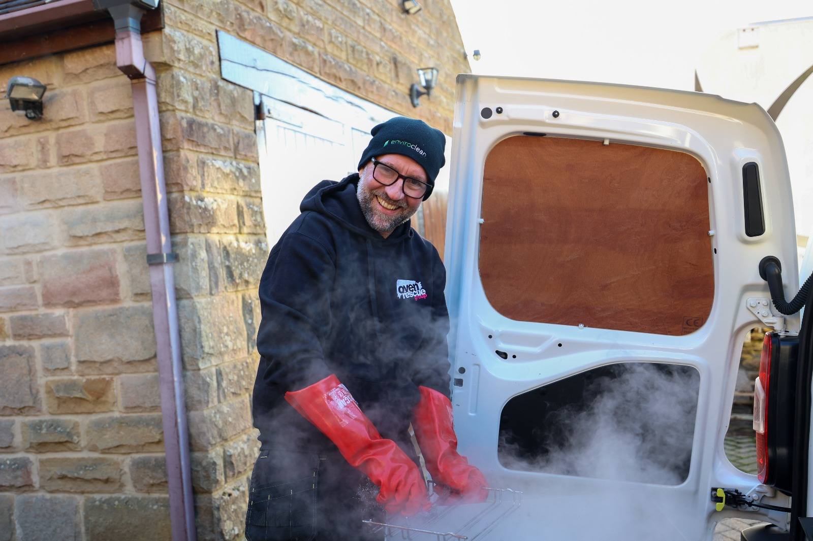 man smiling, cleaning an oven